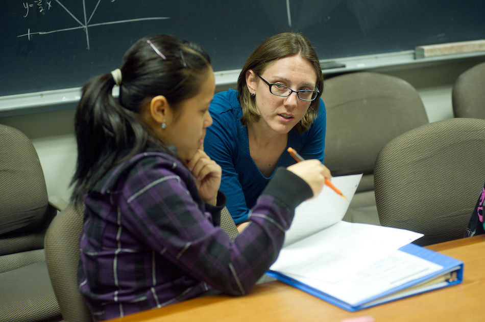 An advisor works with a student over a laptop. 