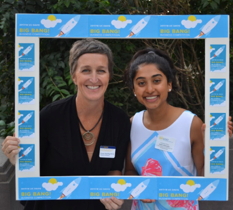 Francesca and a friend hold up a picture frame. 