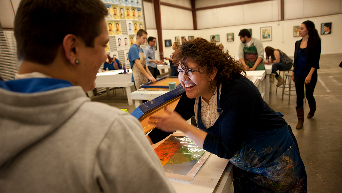 UC Davis student Gilda Posada, right, helps Ricardo Pizano with screen prinking