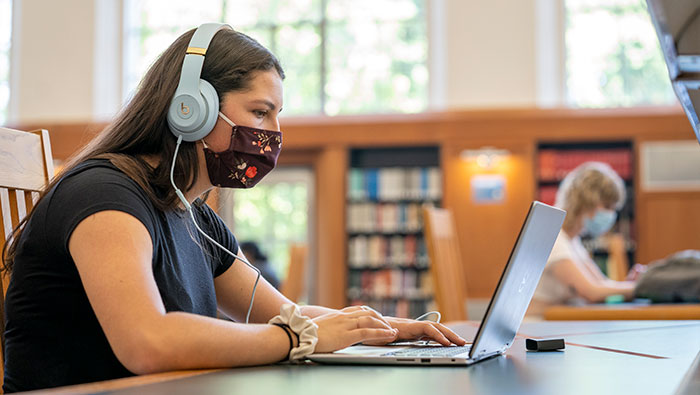 Student studies in library with laptop