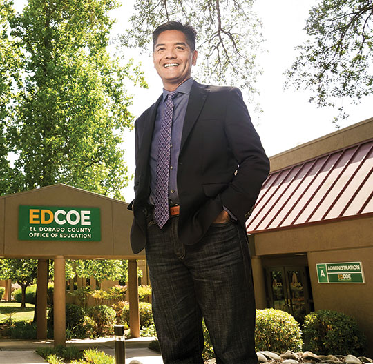 A man stands in front of a school administration building