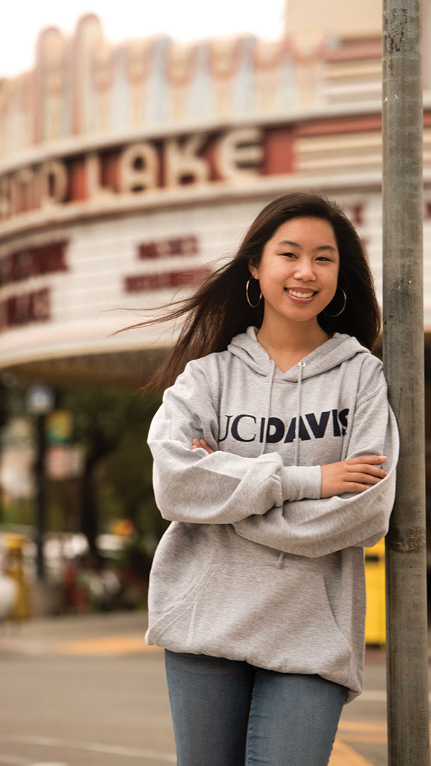 A student stands on a city street in front of a vintage theater