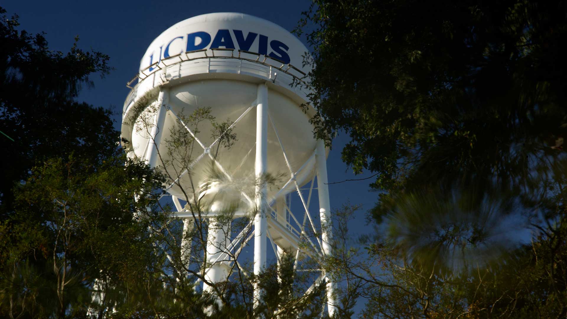 A water tower appears in a large reflection in water.