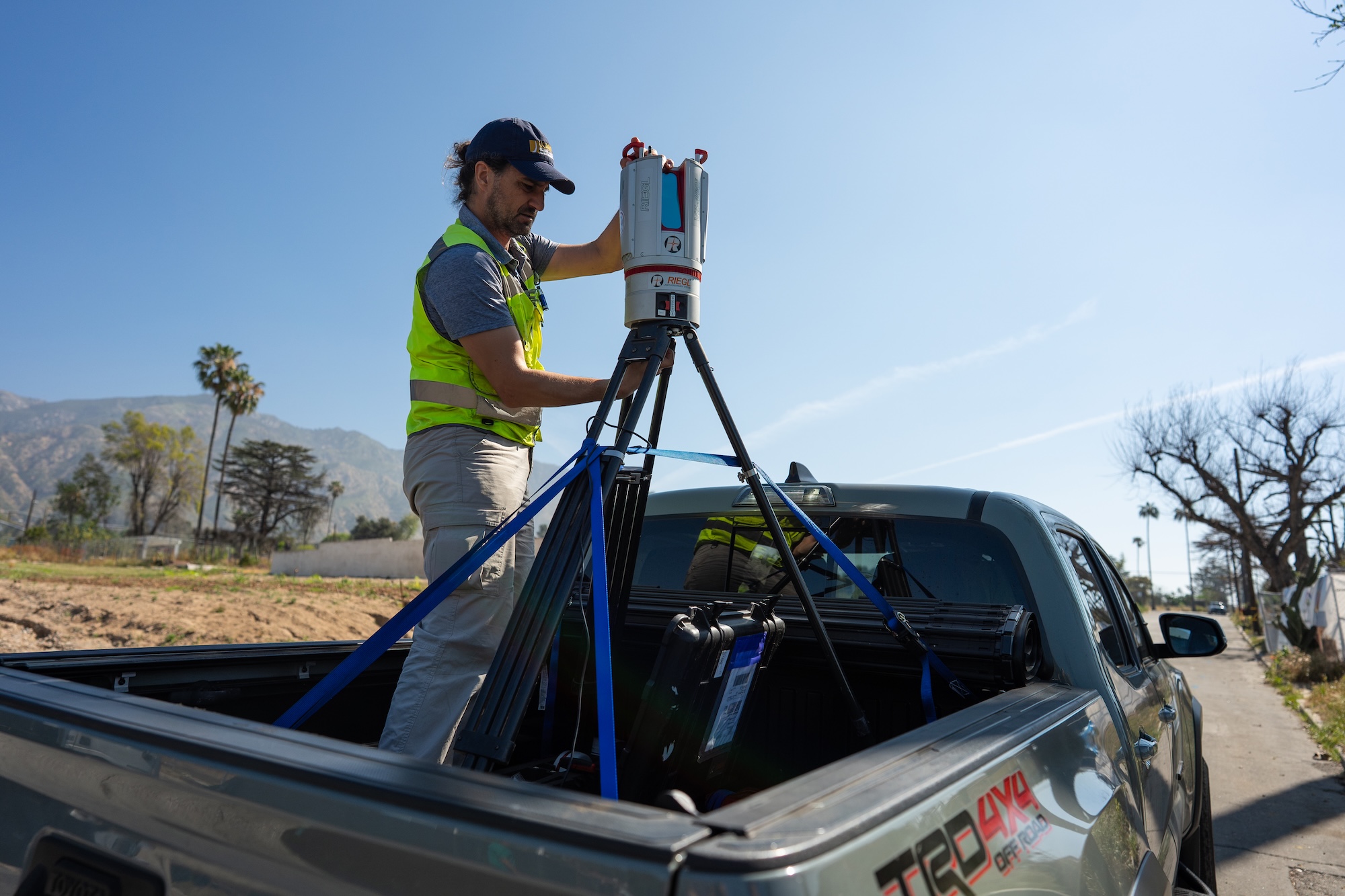 UC Davis plant scientist Alessandro Ossola in safety vest using tripod-mounted 3D LIDAR in pickup bed in Altadena. (Jael Mackendorf / UC Davis)