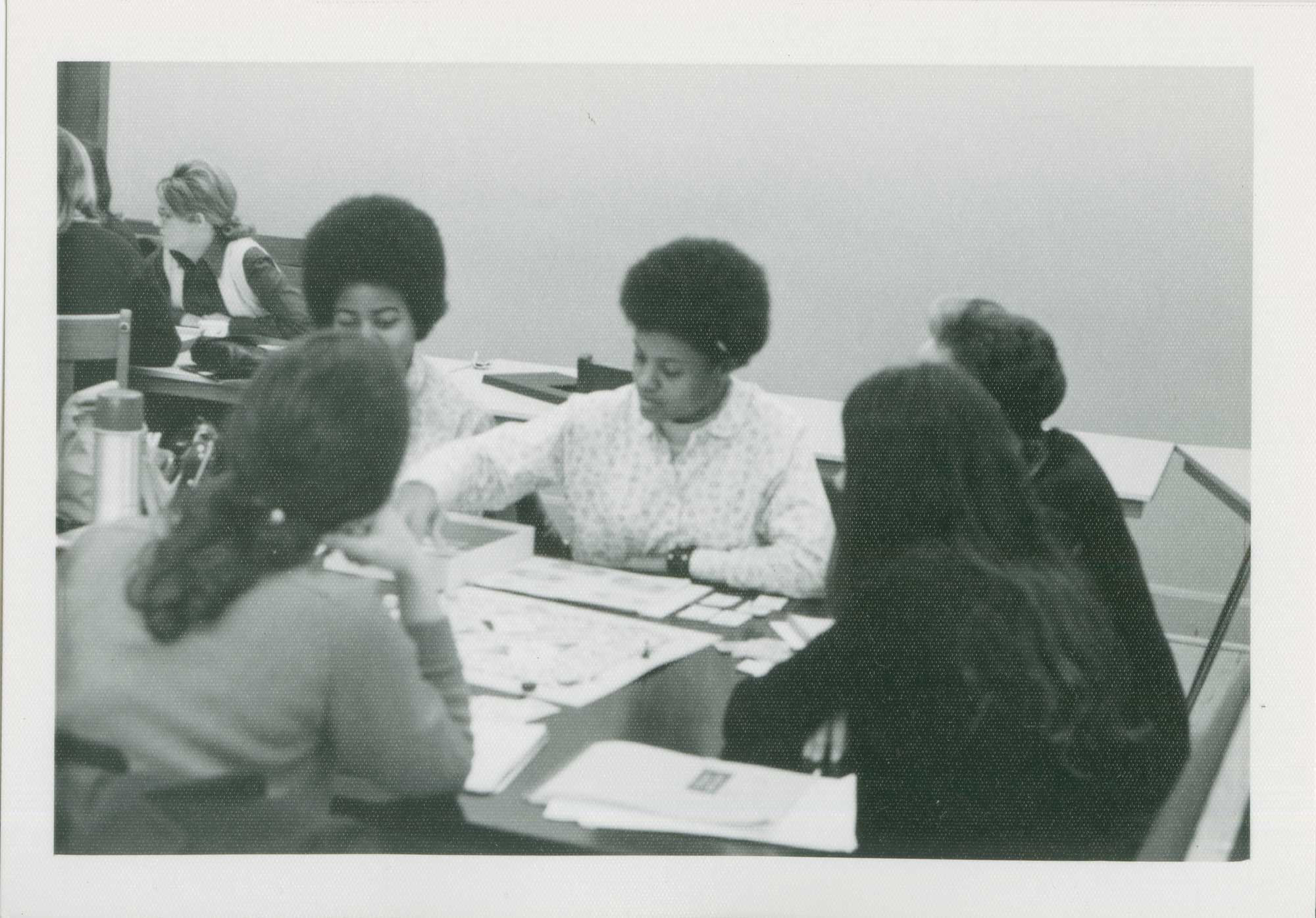 An old photo of five people sitting around playing a board game