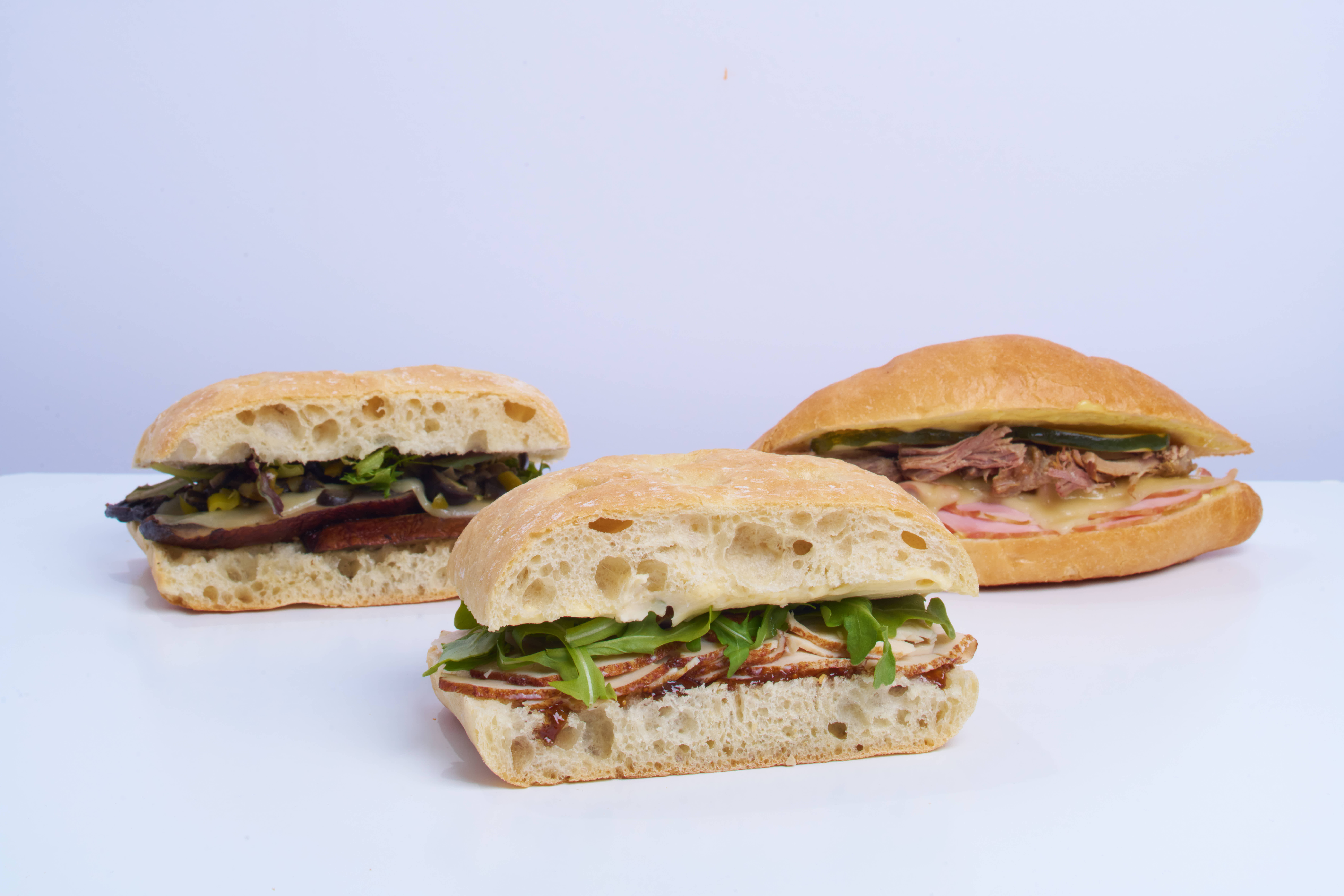 Three different toastie sandwiches are arranged in a photo shoot format against a white background and countertop.