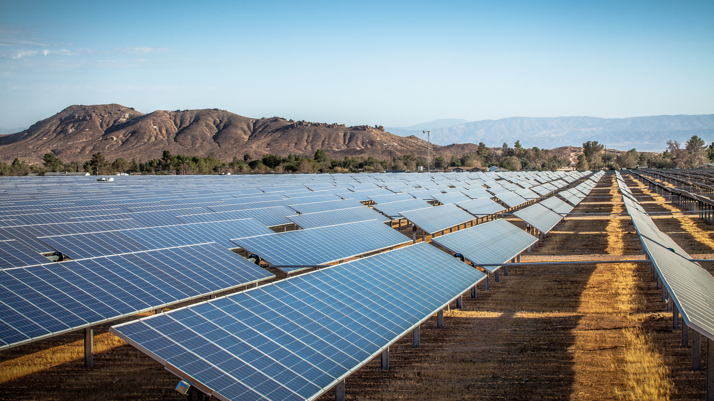 ground solar panels reflect sunlight with mountains in distance in Mojave Desert