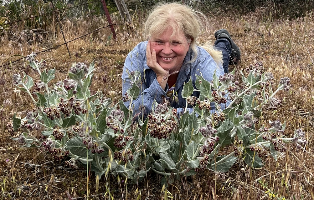 Elizabeth Crone posing by a bush of flowers