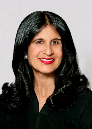 Smiling woman with long black hair wearing black judicial robe
