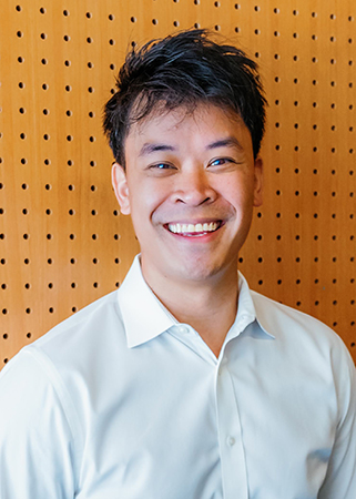 Smiling young man in white shirt headshot against pegboard background