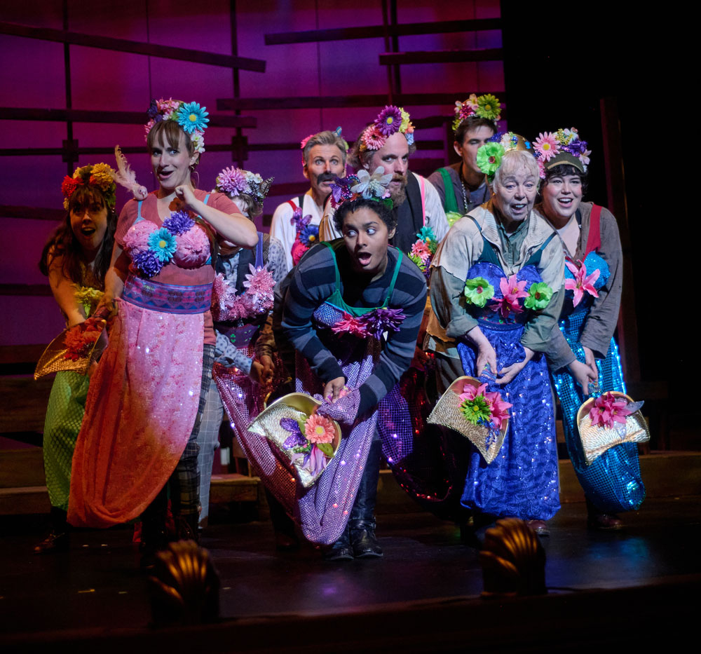 Theater group on stage in colorful costumes for Peter and the Starcatcher