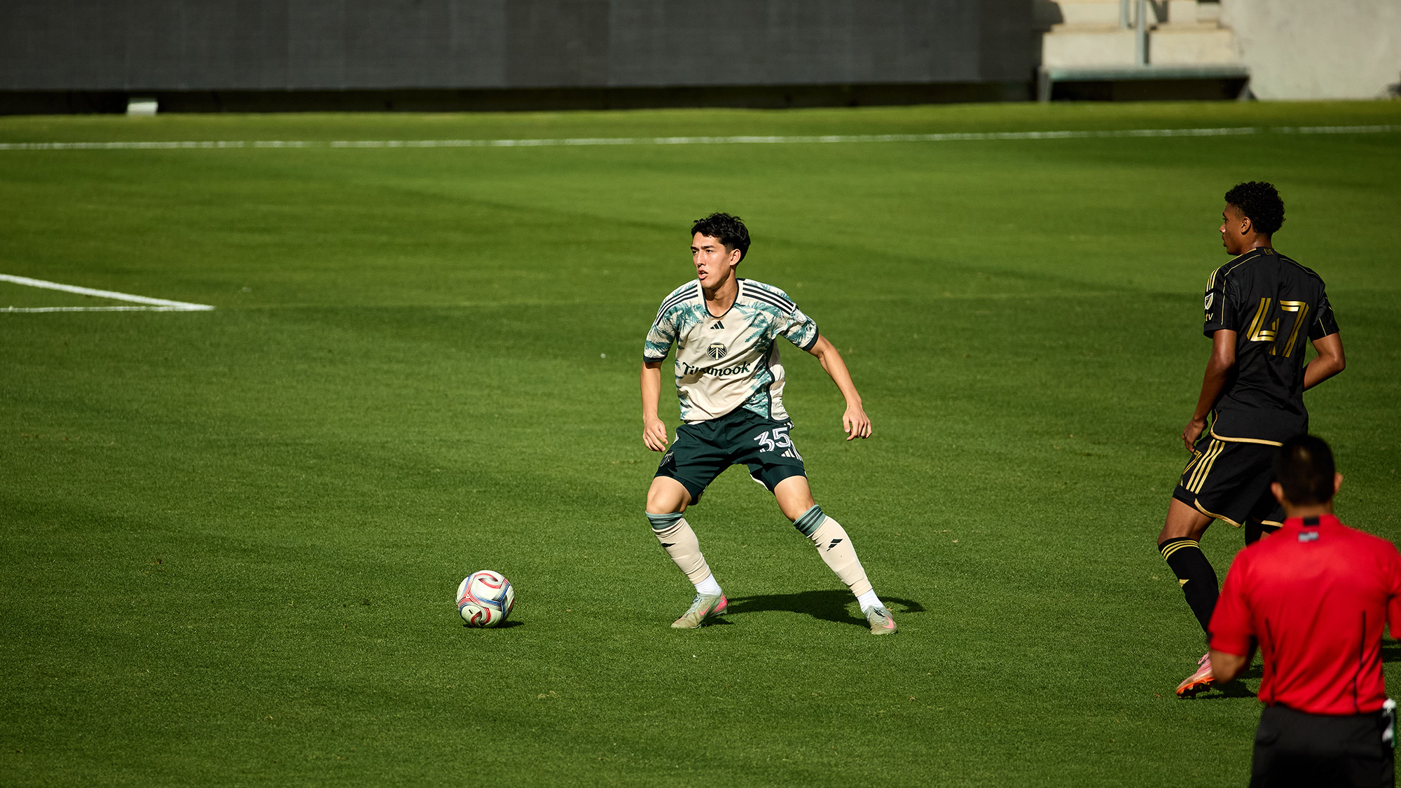 A young soccer player in a patterned jersey with a ball on a green field.