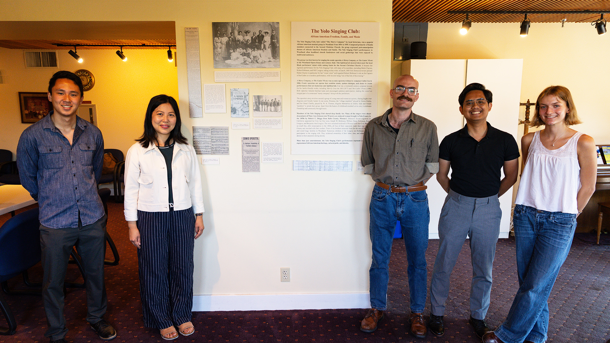 Group of people stand in front of a history display in the lobby of the Woodland Opera House