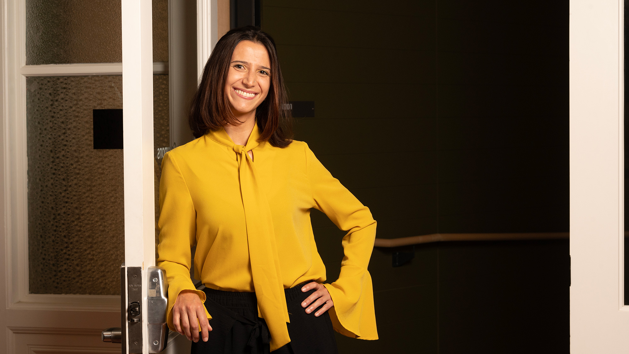 Woman stands in doorway with one hand on hip