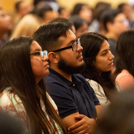 profile of student in a row listening to a speaker