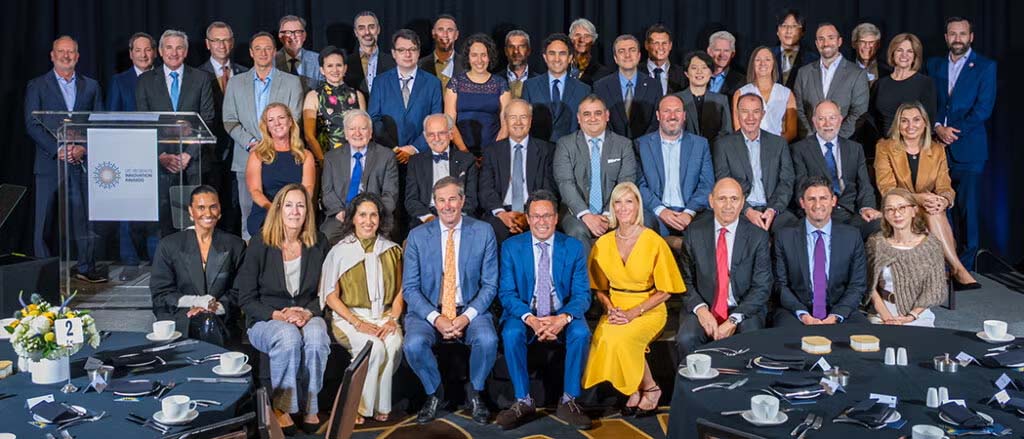 About 40 people in formal attire posed on stage at a gala