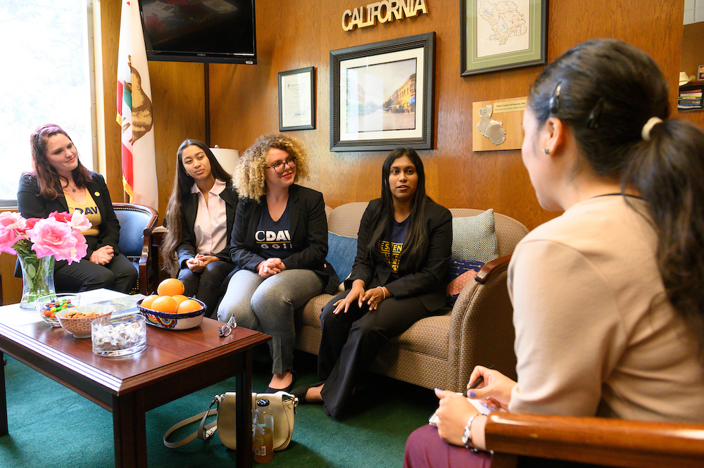 Political science majors sit on a coach in a stately office to advocate for their rights. 