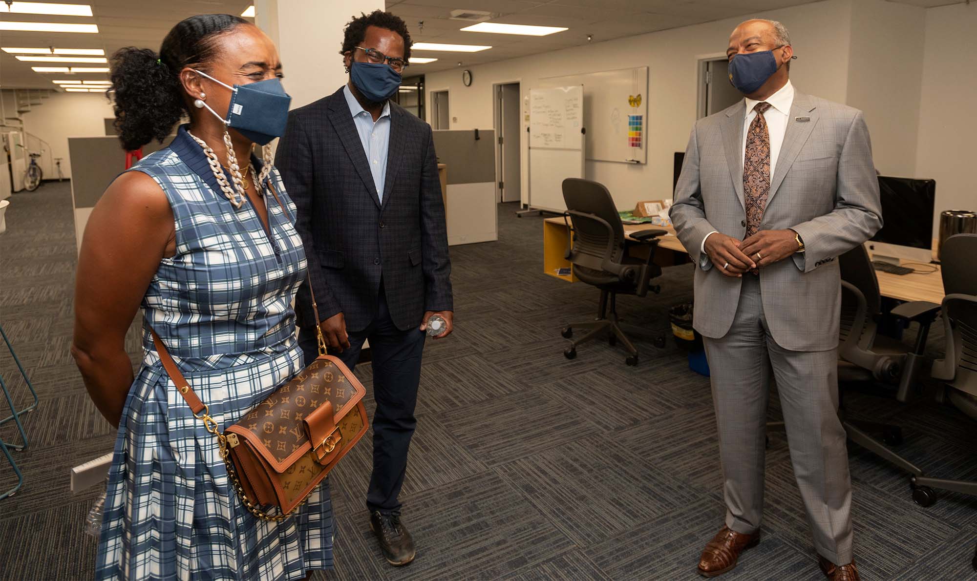 Maisha Winn and Torry Winn talk with Chancellor Gary S. May outside the recording studio.