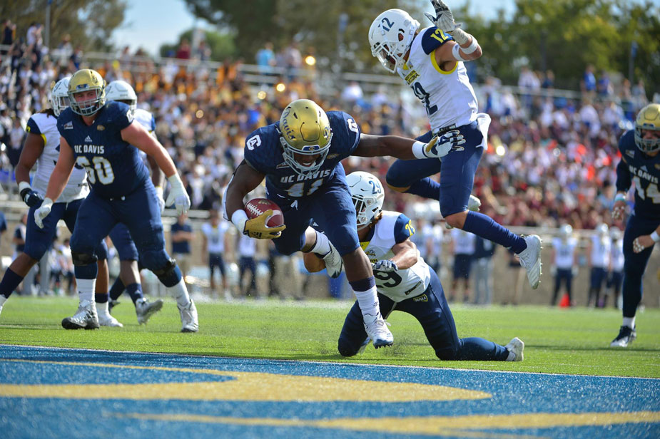 Aggie football players carries ball into endzone.