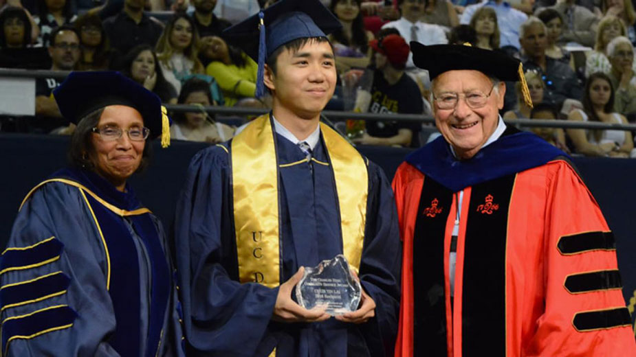 Helene Dillard and Charles E. Hess flank student, all three in commencement regalia.