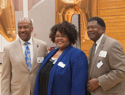 3 administrators pose in high school gym.