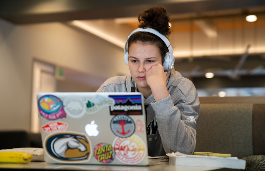 Player with headphones on, staring at laptop screen.