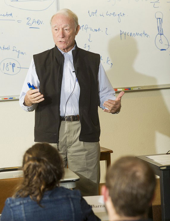 Michael Lewis, teaching, in front of whiteboard.