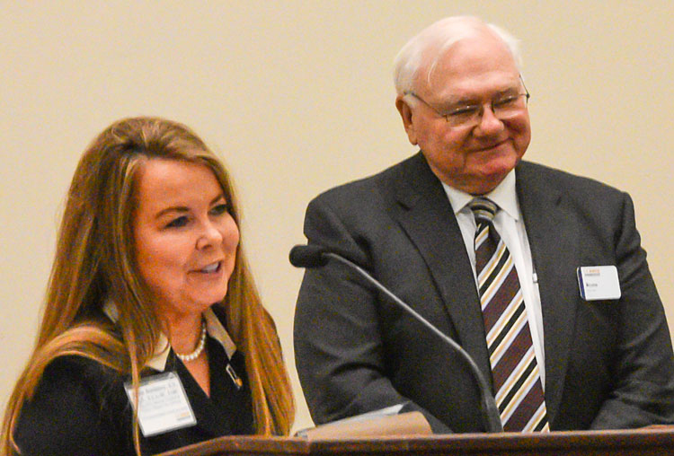 Woman at podium, man behind her.