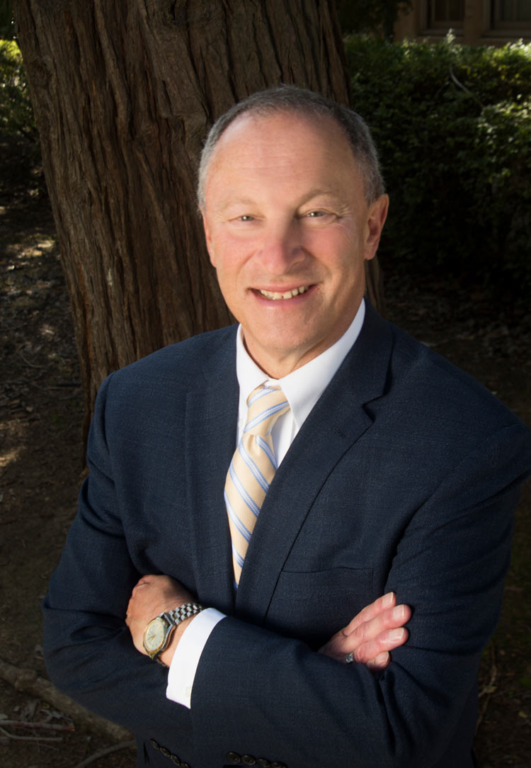 Ralph J. Hexter, in suit, arms folder, portrait under a tree.