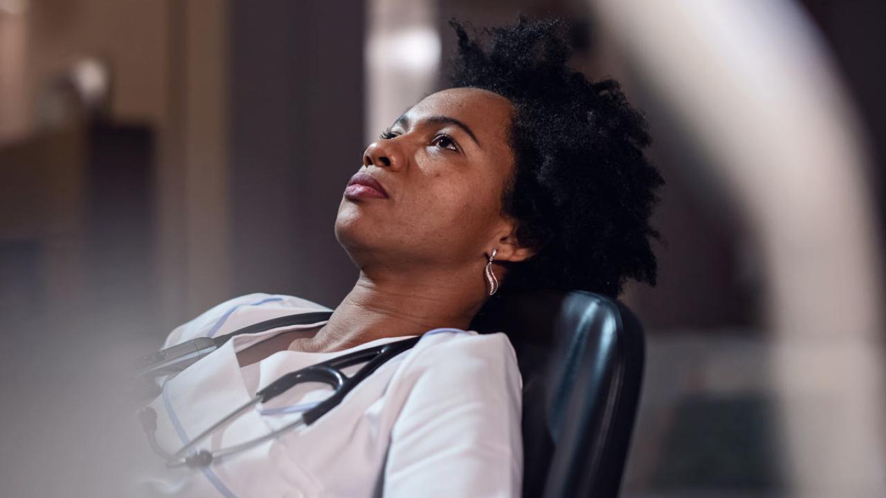 Doctor leans back in chair, reflecting.