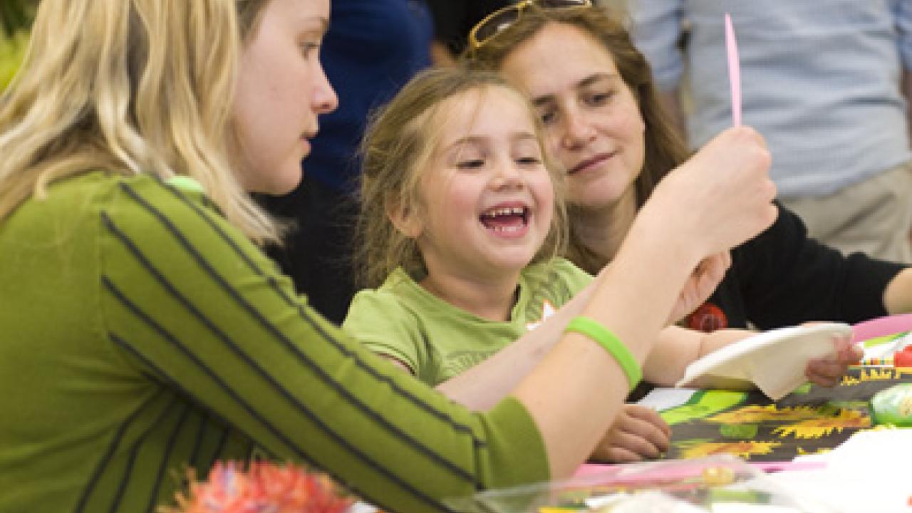 Noah Vinokurov works on a mask-decorating project with assistance from Jaime Reed, left. Also pictured is Noah's mother, Michal Kurlaender.
