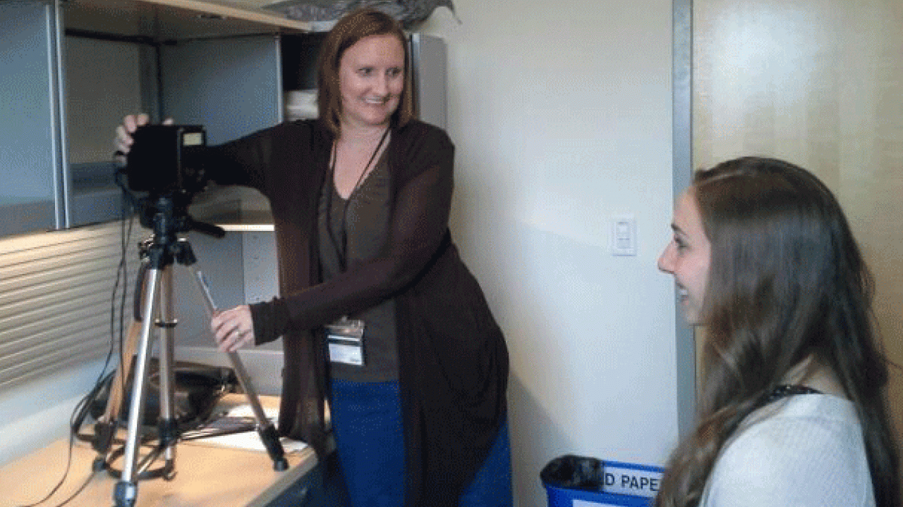 Photo: Woman takes an employee&rsquo;s photo for AggieCard.