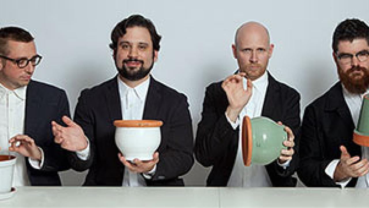 four men in tuxes making music on flower pots