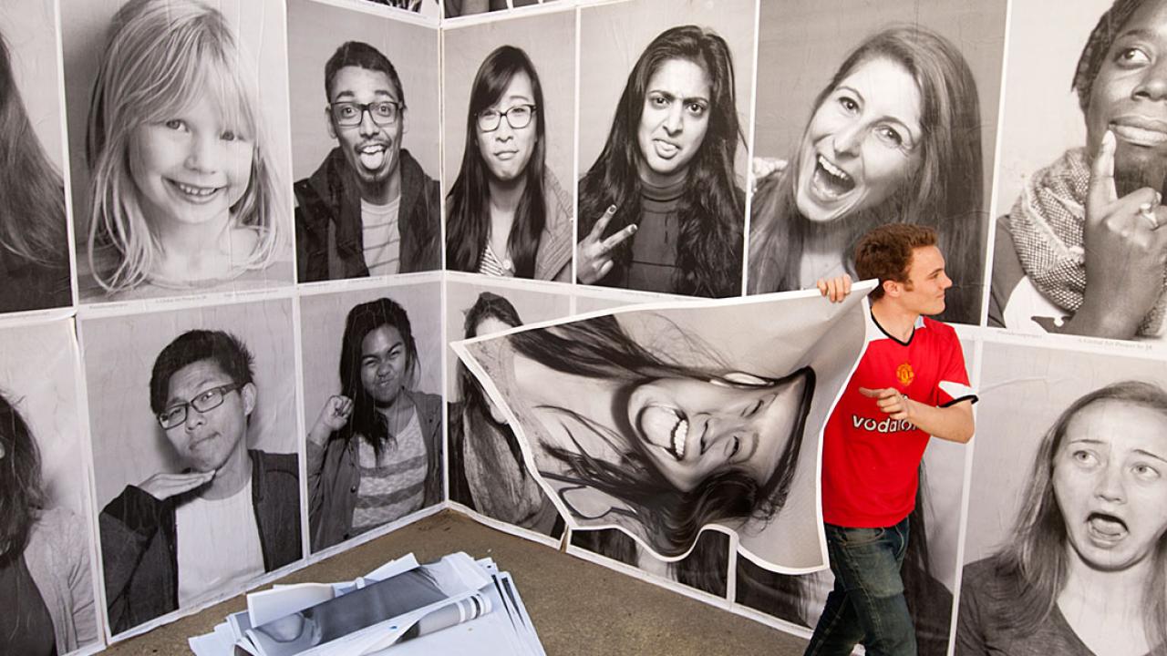 Student puts posters up on a building wall.