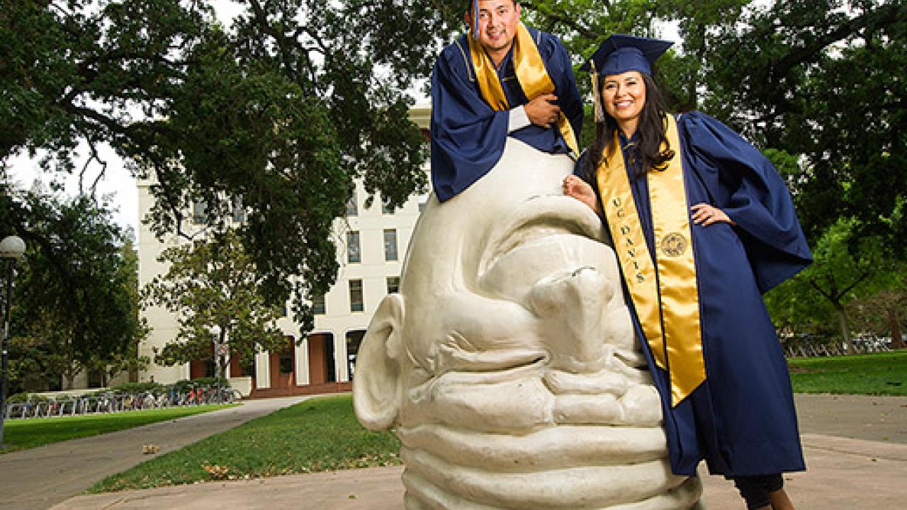 Miguelangel Turcios, left, and his sister, Christy, pose in graduation gowns on an Egghead sculpture.