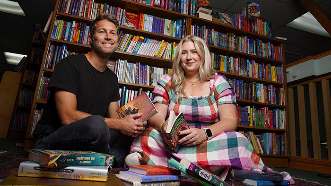 Brett and Erin Arnold sit on the floor of their bookstore with several books around them