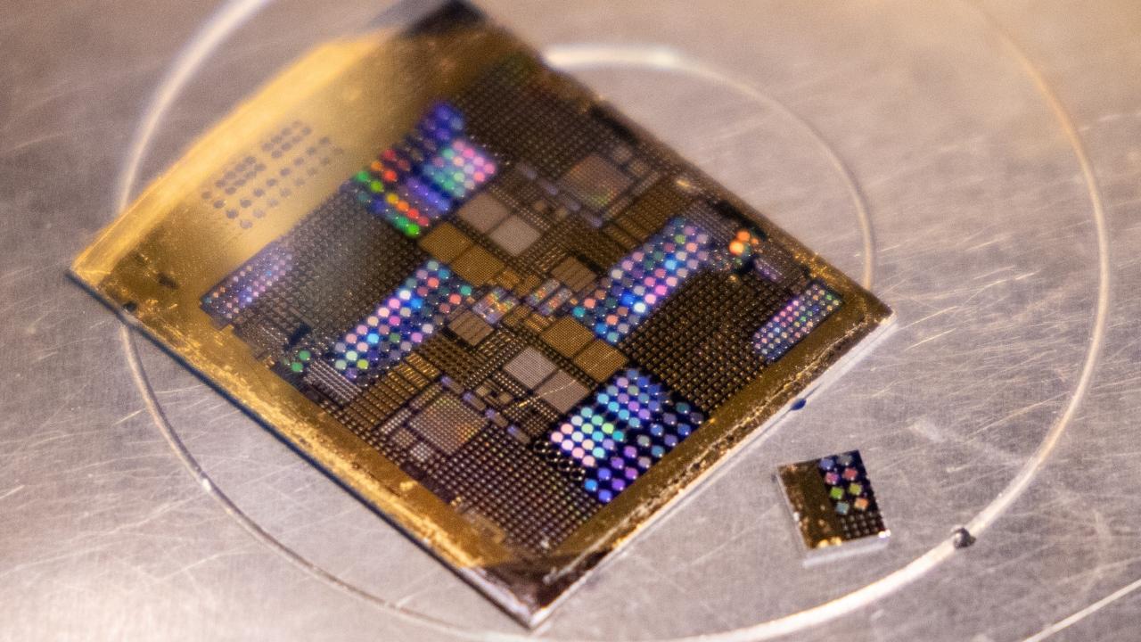  A rectangular piece of gold-colored metal printed with regular squares of different sizes and rows of colored dots. 