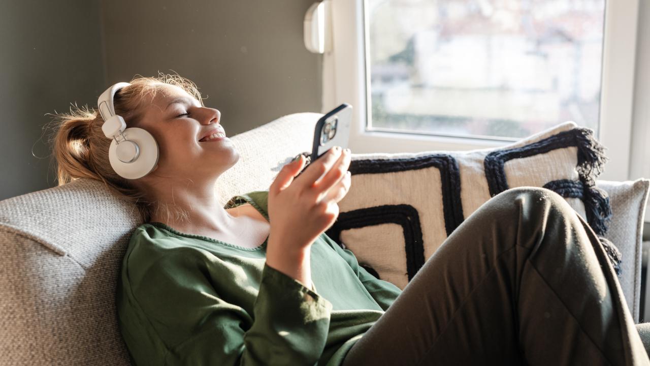 Woman sitting on couch listening to earphones