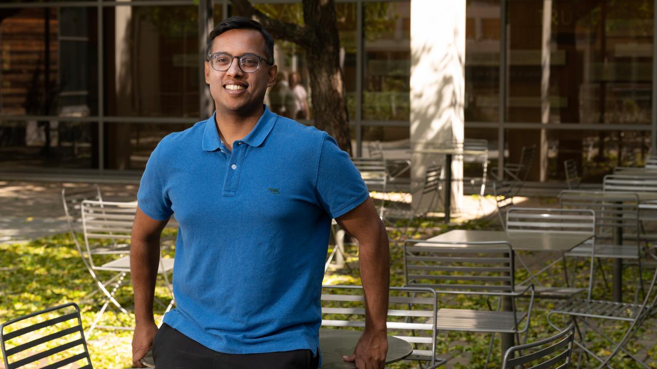 Man leans against a table in an outdoor patio