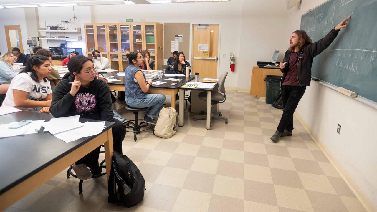 Teaching assistant talks to students in classroom