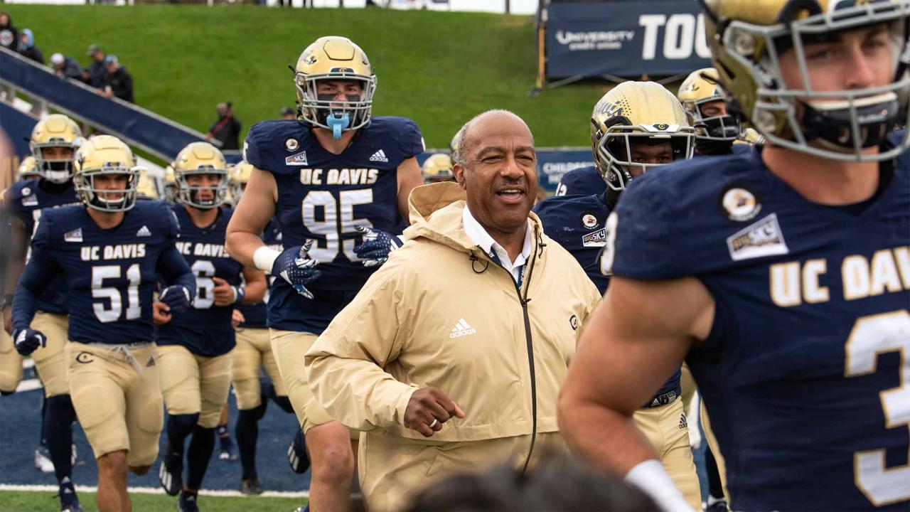 Chancellor Gary S. May runs next to many football players