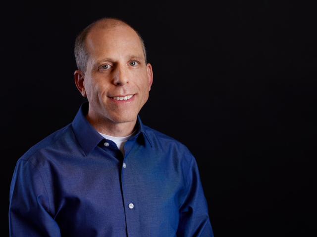 Man in a blue shirt with a black plain background