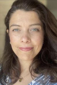 Photograph of a smiling woman with long dark hair and light green eyes