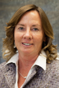 Smiling headshot of a middle-aged woman with shoulder-length light brown hair, gray blazer