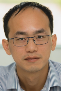 Man with dark hair, glasses and blue shirt
