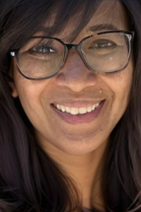 Smiling woman with glasses and dark hair, close-up portrait