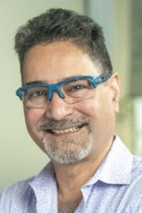 Smiling middle-aged man with blue glasses and light patterned shirt