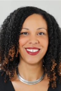 Woman with dark curly hair and red lipstick smiling