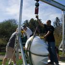 Workers from Ship Art International use a gantry to hoist one of the Eggheads.