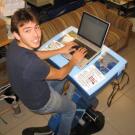 Graduate student Tai Stillwater is pictured on the Pedal Powered Charging Table, a project that he worked on.